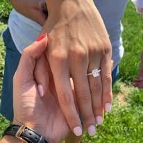 Close-up of hands, one with an engagement ring.