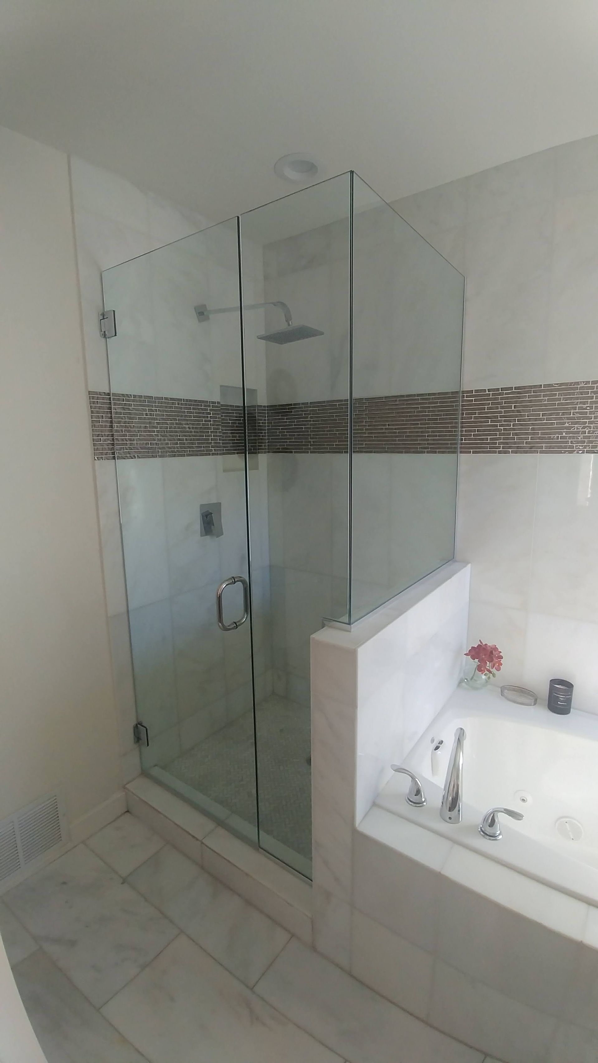 A bathroom with a glass shower door and a bathtub.