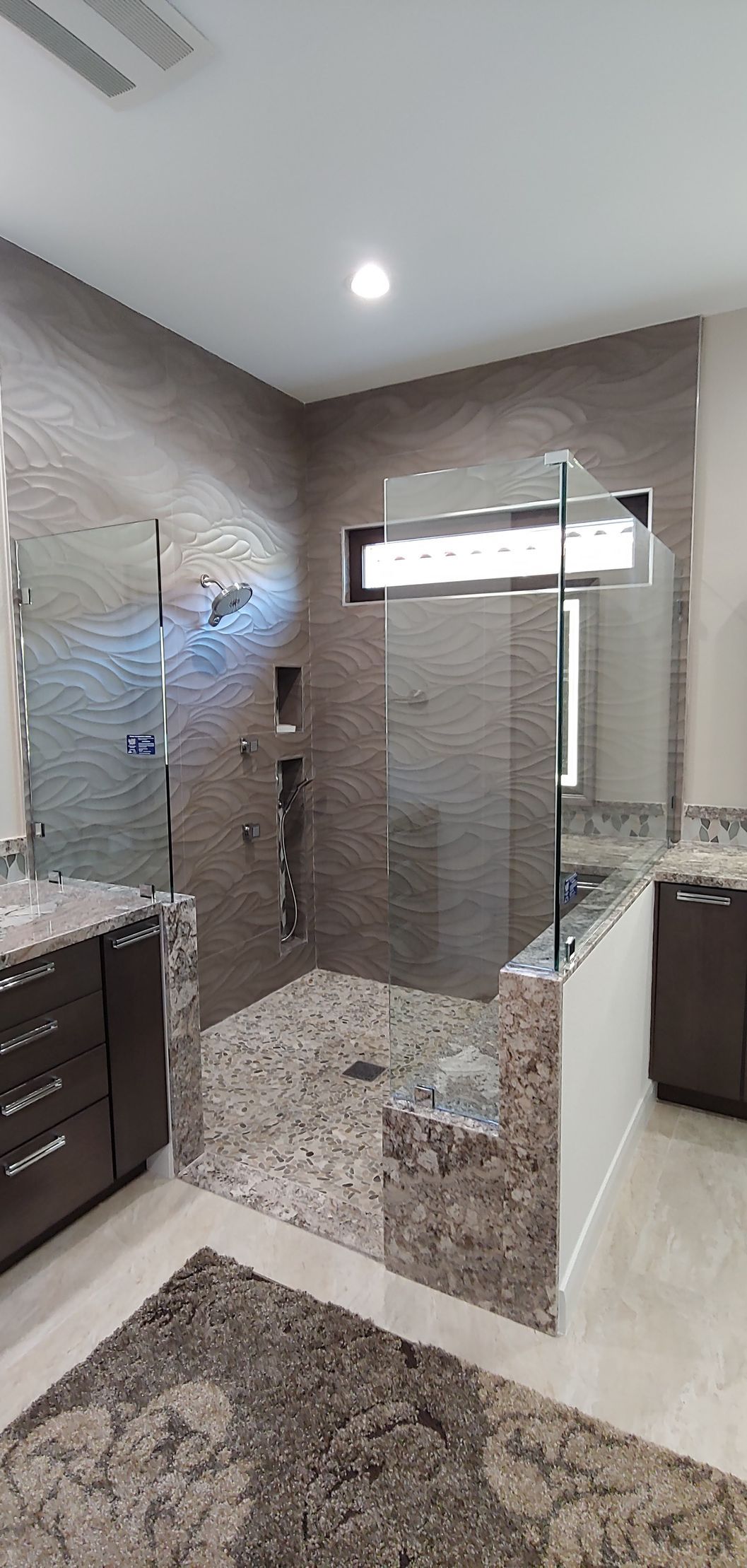 A bathroom with a walk in shower and two sinks.