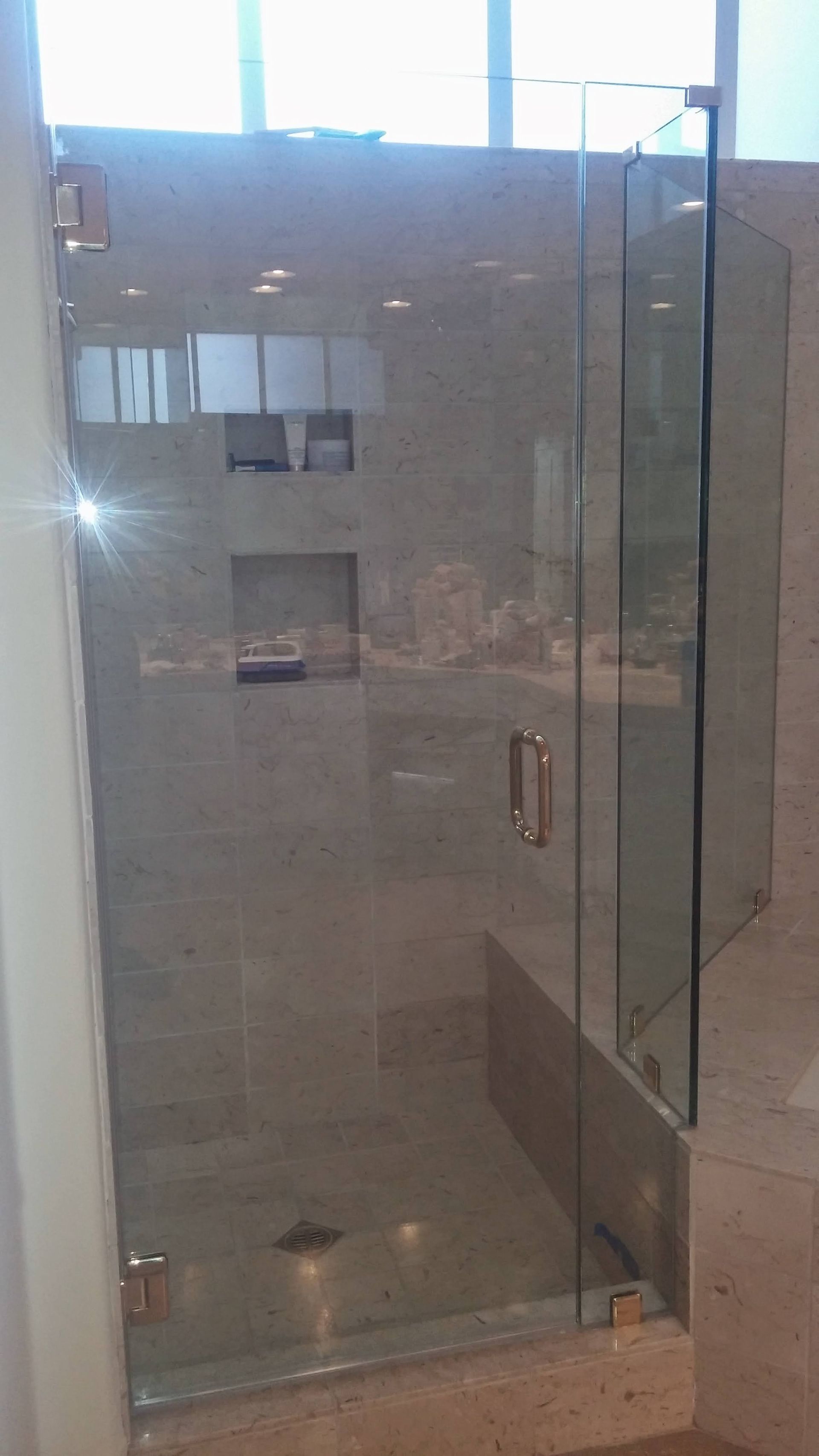 A bathroom with a glass shower door and a window.
