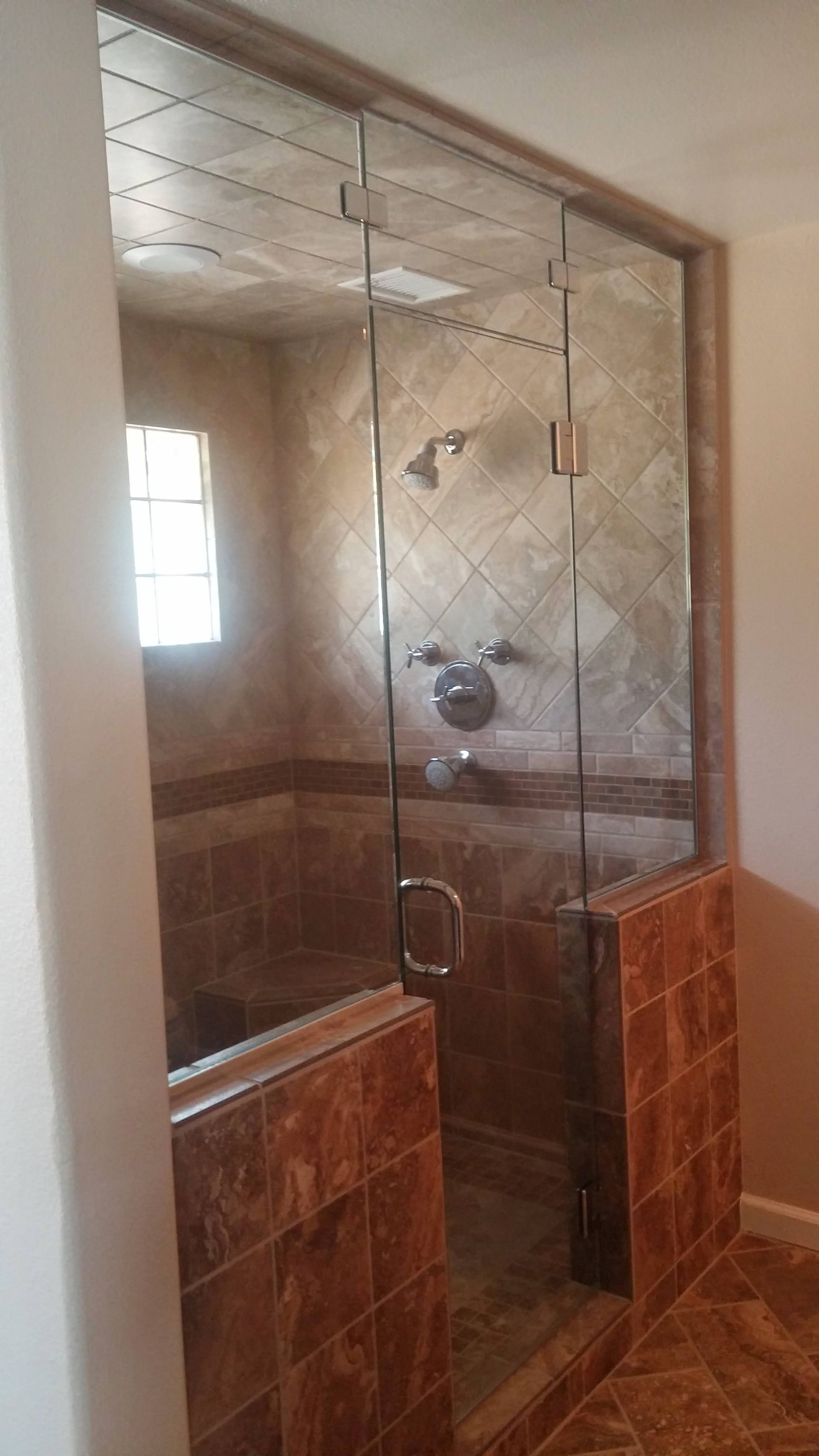 A bathroom with a walk in shower with a glass door.