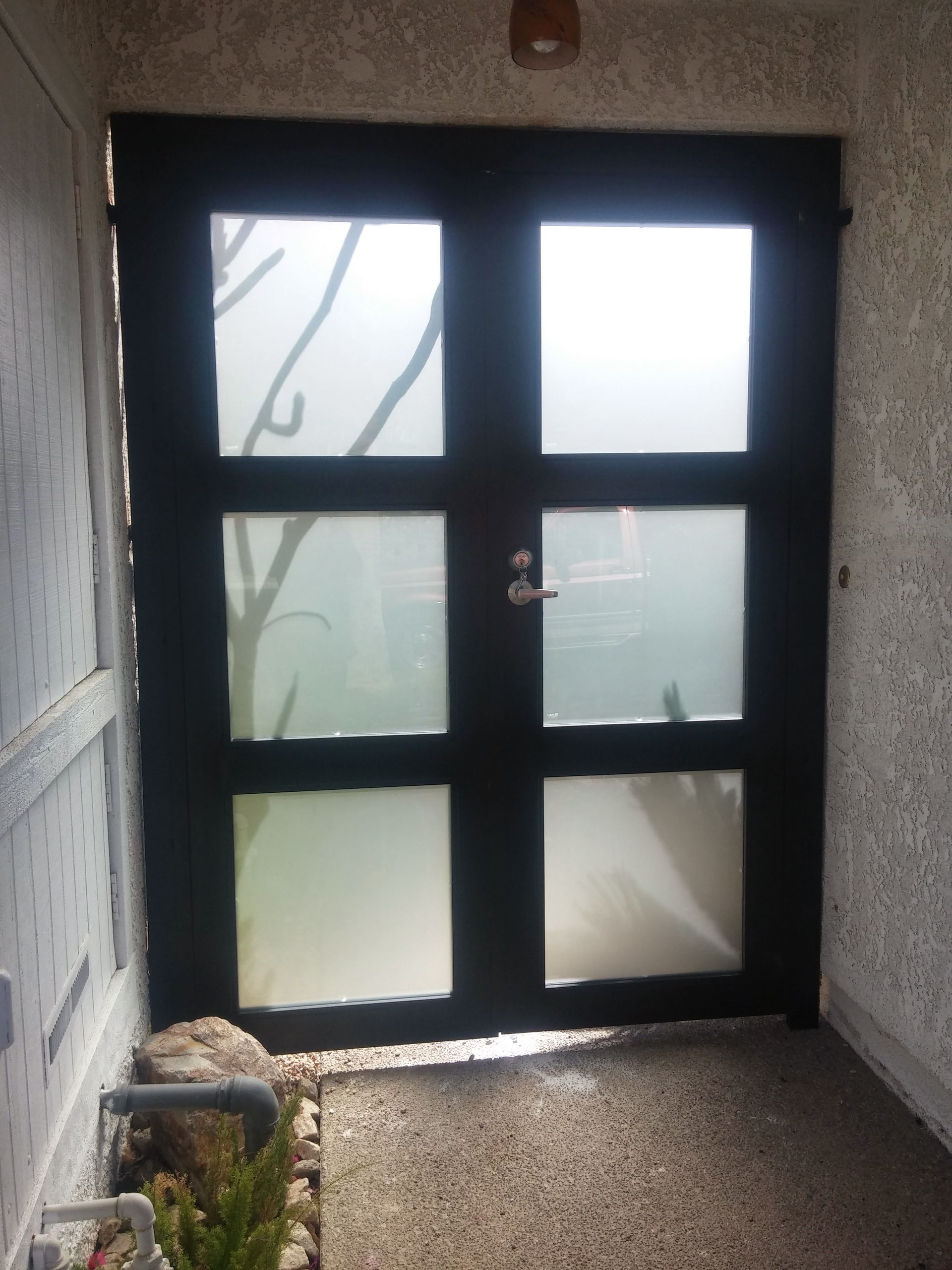 A black door with frosted glass in a hallway