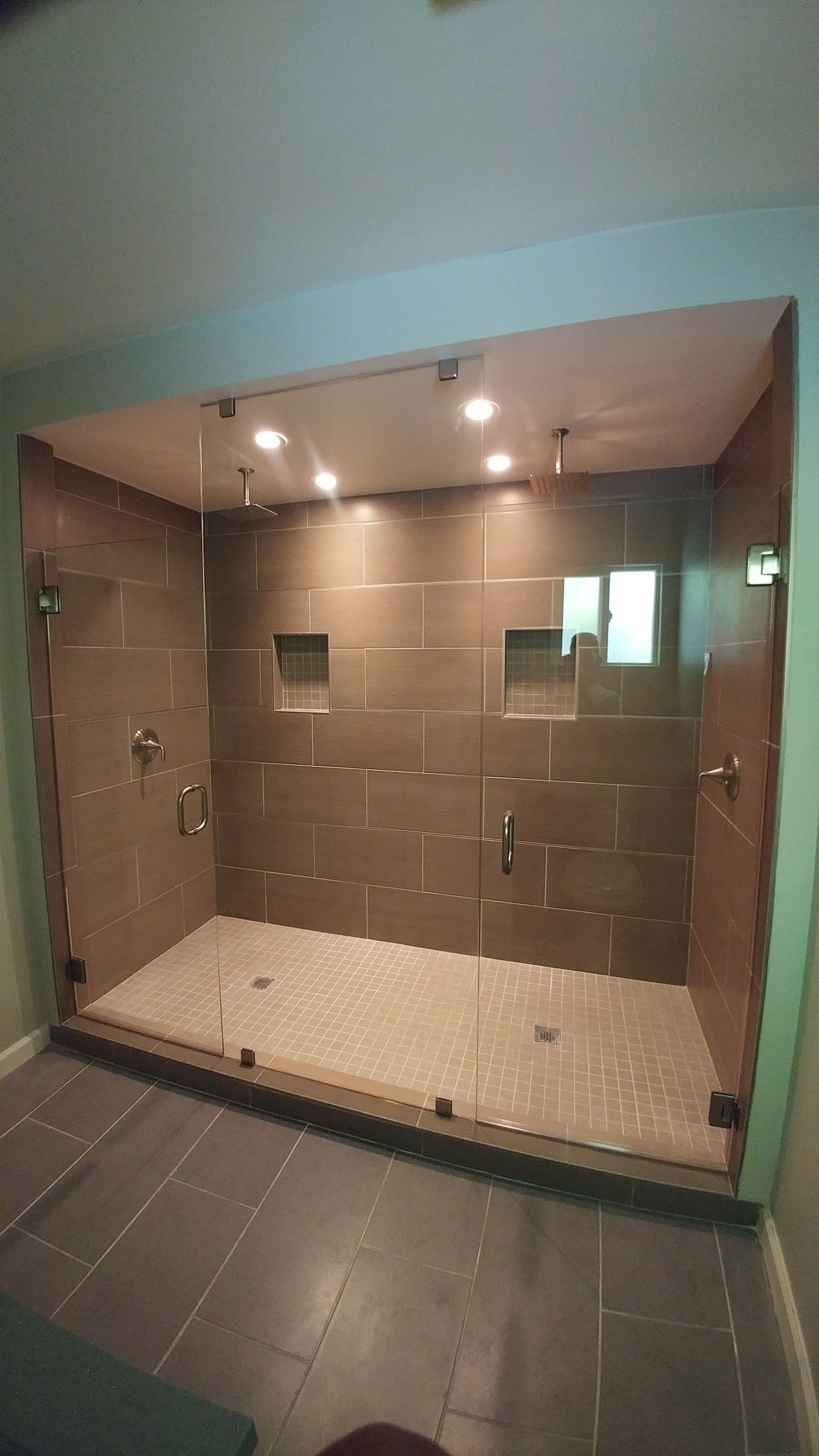 A bathroom with a walk in shower with a glass door.