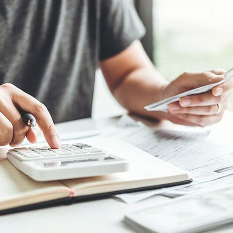 Person using a calculator and holding a credit card over paperwork at a desk