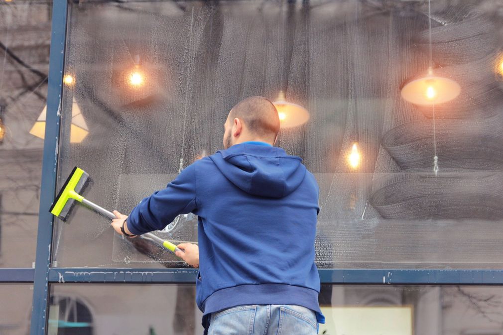 Person pressure-washing a wooden deck with a black hose nozzle