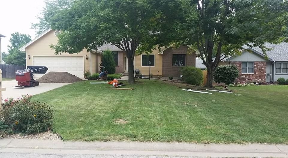House with a lawn; two trees in front.  Lawn work in progress; dirt pile to the left, equipment present.