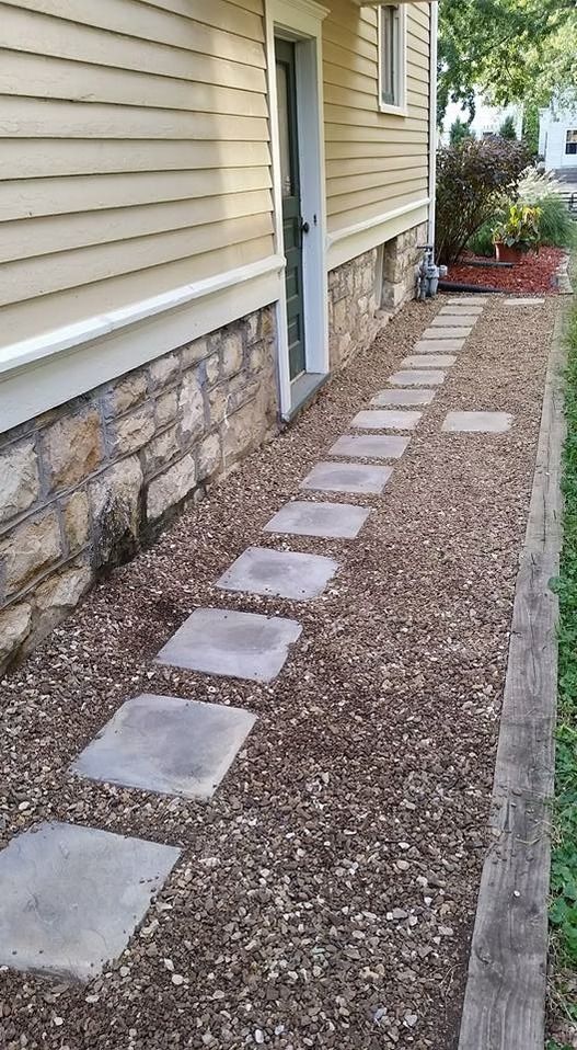 Pathway of square stones in gravel beside a house with a door, and a retaining edge.