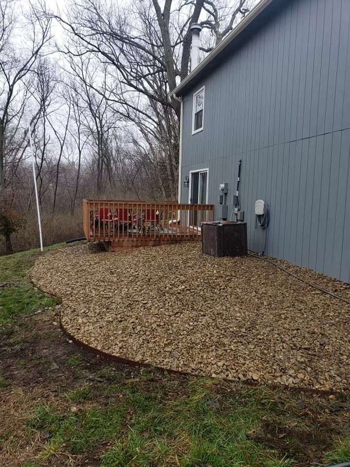 Backyard with a wood deck, gravel bed, and gray siding on a house.