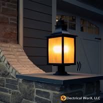 A lantern is sitting on top of a stone pillar in front of a house.