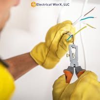 A man wearing yellow gloves is cutting a wire with a pair of pliers.
