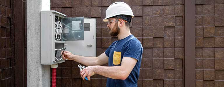 A man in a hard hat is working on an electrical box.