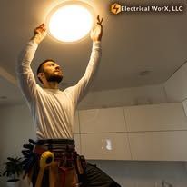 A man is changing a light bulb in a kitchen.