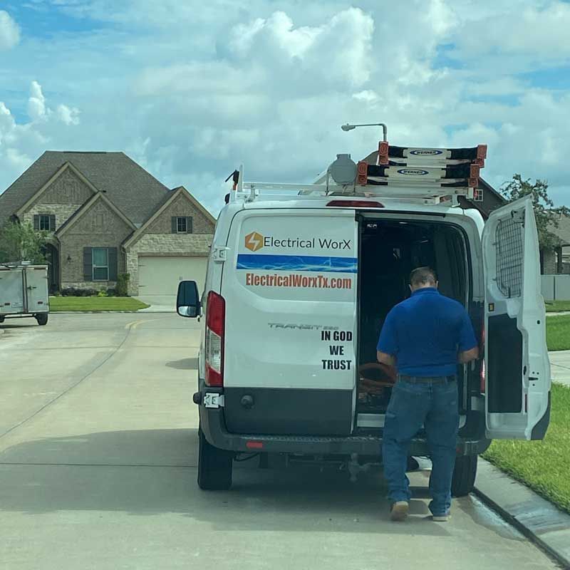 A man in a blue shirt is getting out of a van that says electrical waste.com