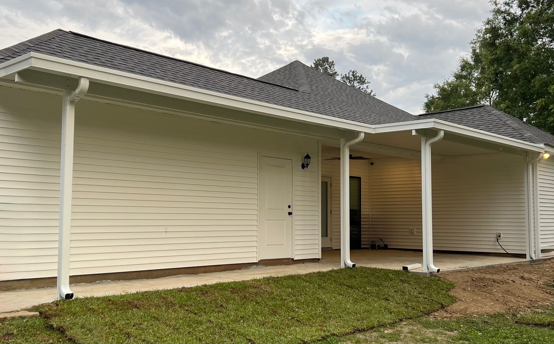 White house with black roof, white trim, and a covered porch.