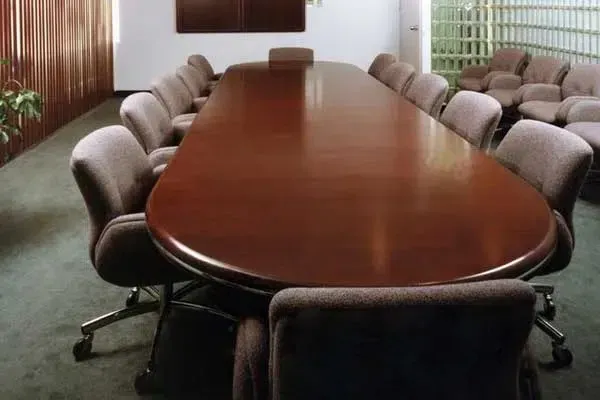 Conference room with a long oval wooden table surrounded by cushioned office chairs