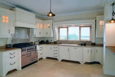 Bright white kitchen with pink stove, tiled floor, pendant lights, and window above the sink