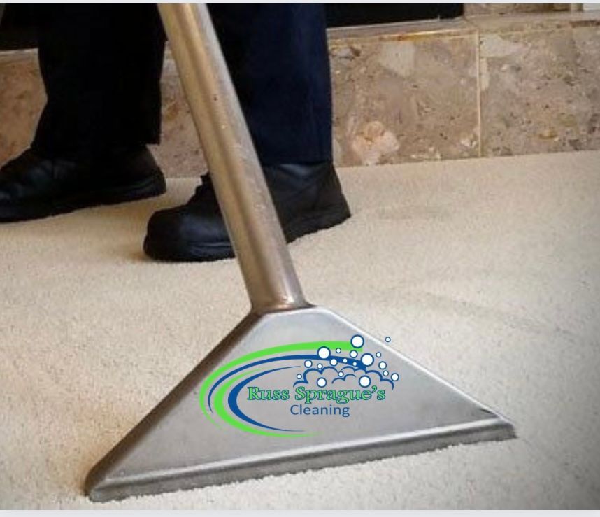 Vacuums cleaning carpet near a tiled floor, with a person’s feet visible in the background.