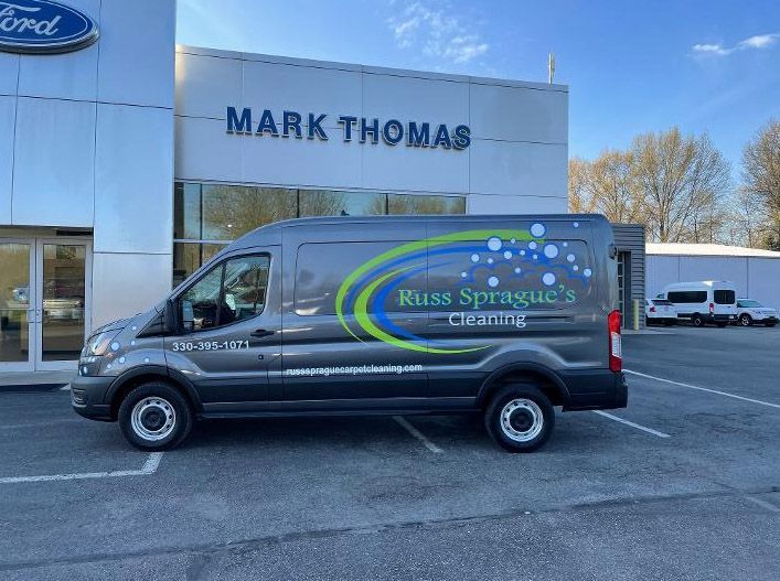 Black service van parked outside a Mark Thomas Ford dealership on a sunny day.