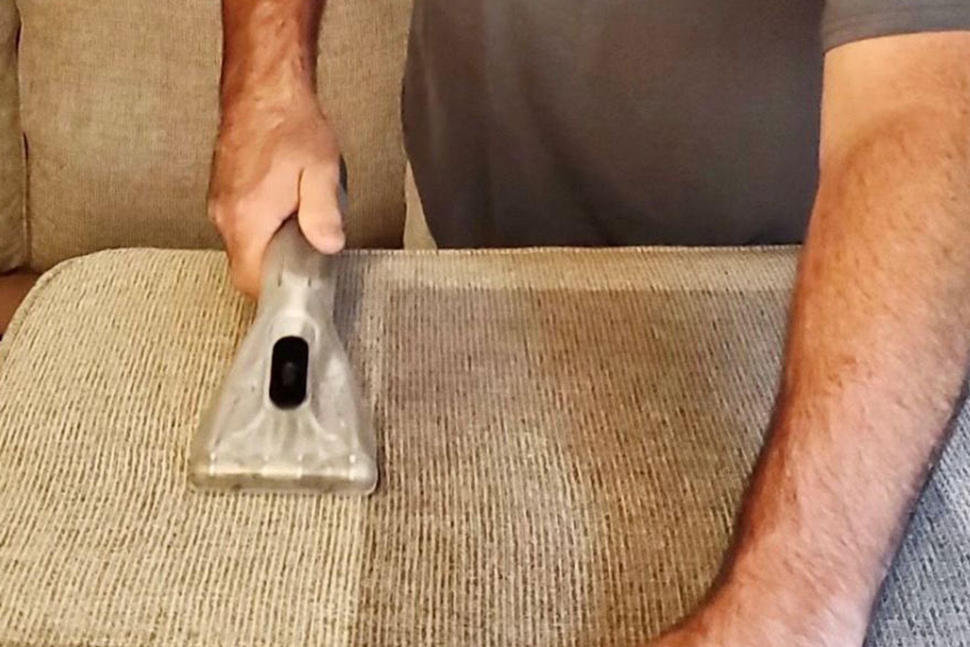 Hands using a vacuum cleaner on a beige carpet