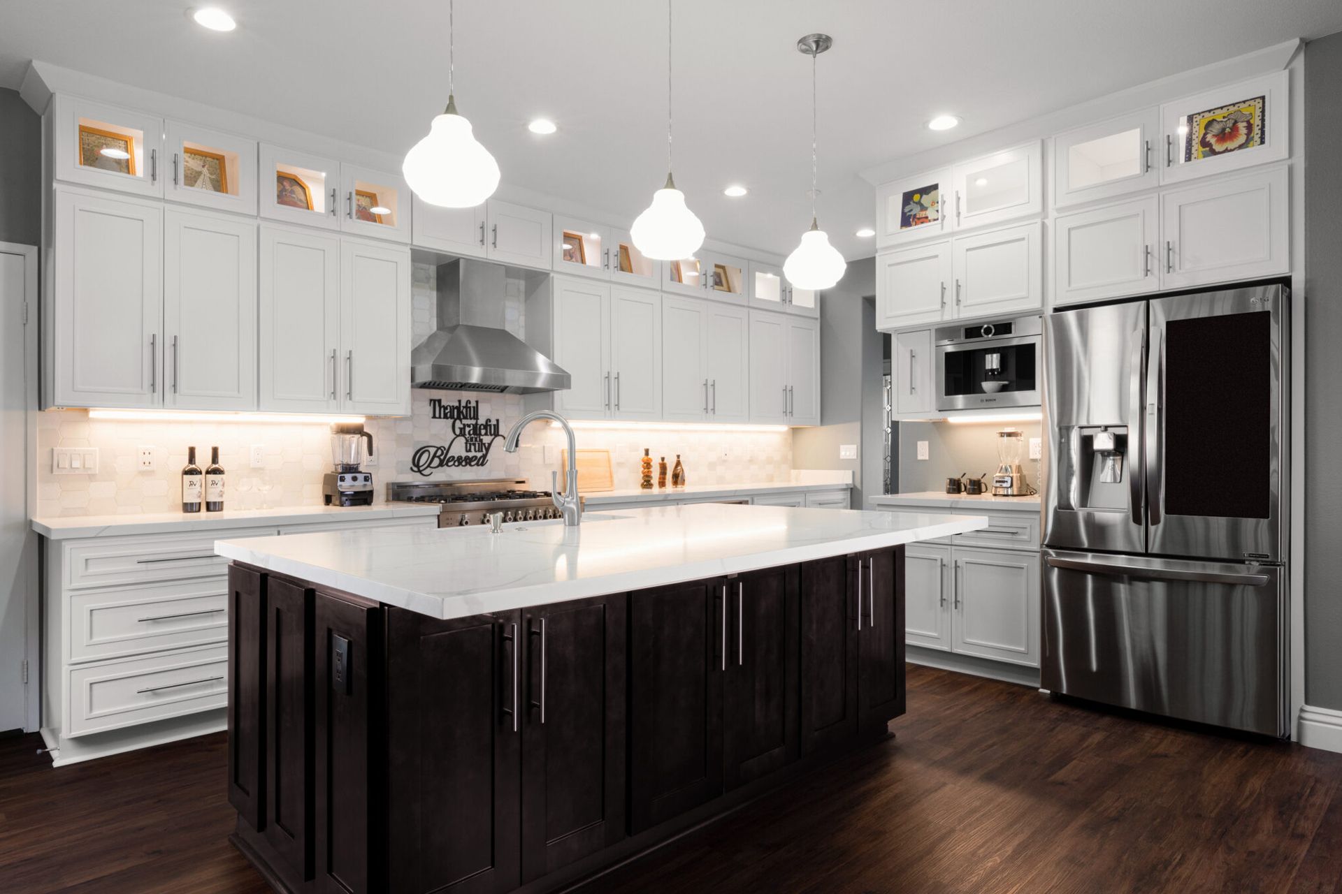 Modern kitchen with white cabinets, dark island, and stainless steel appliances.