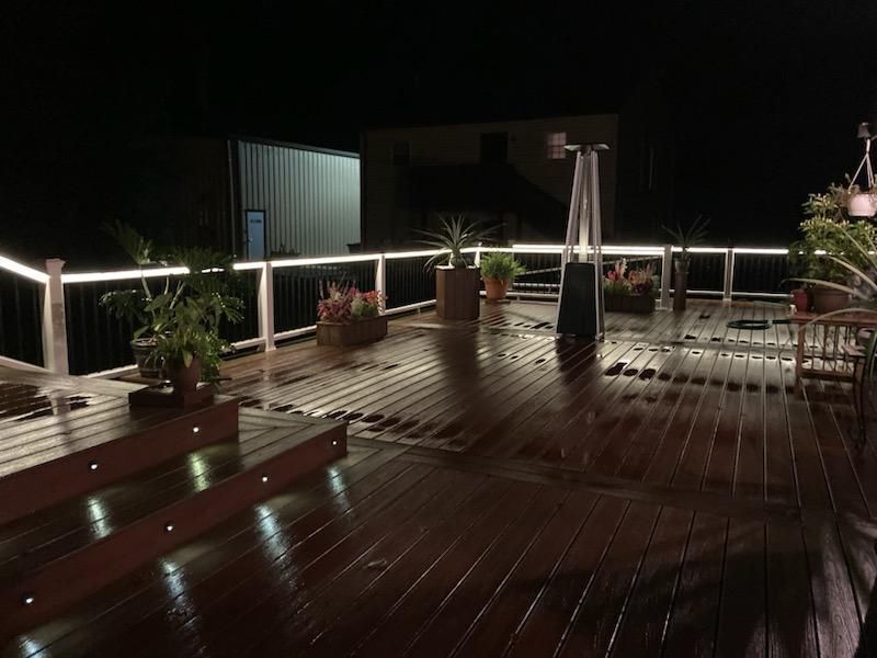 A deck with a heater and planters on it at night.