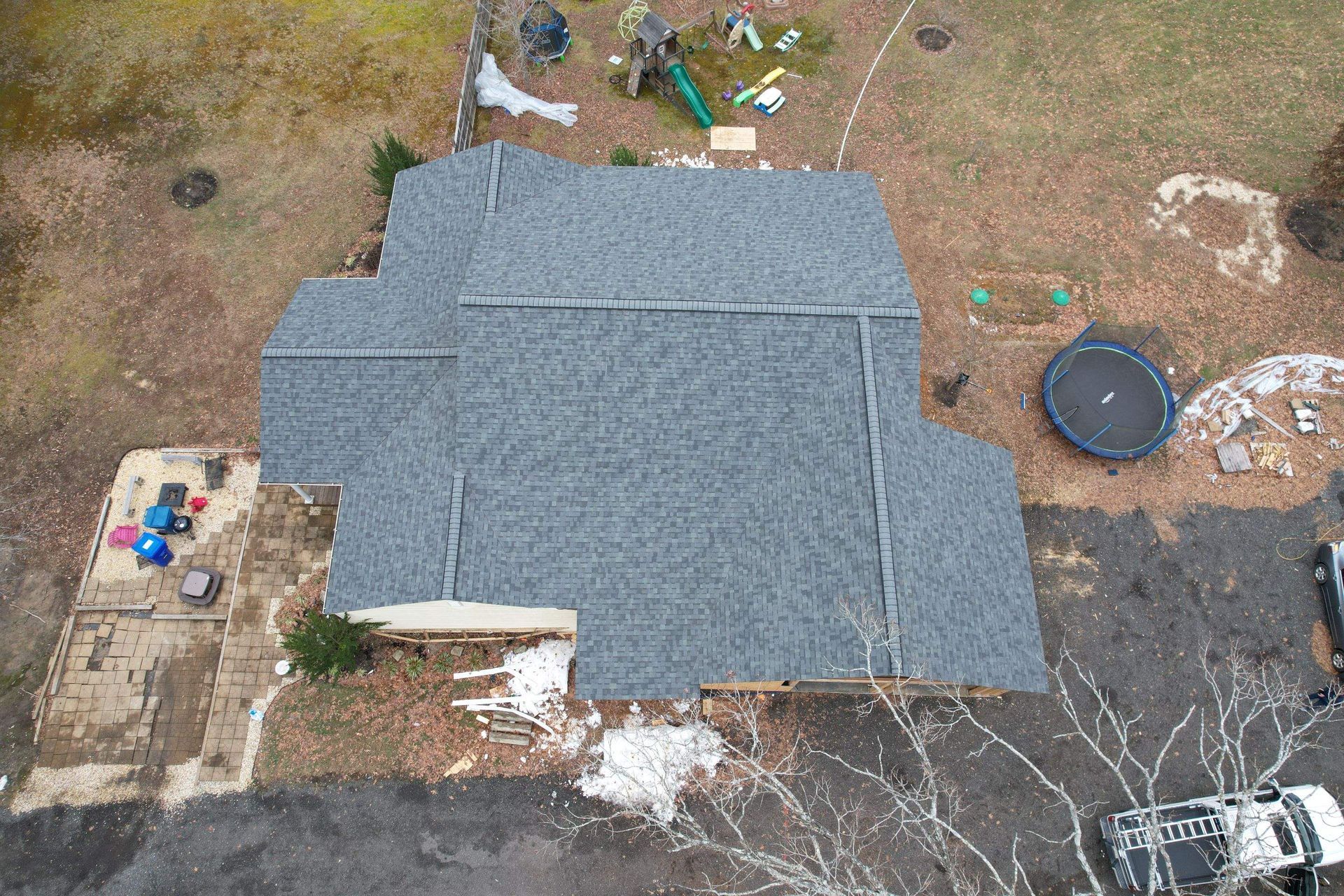 An aerial view of a house with a trampoline in the backyard.