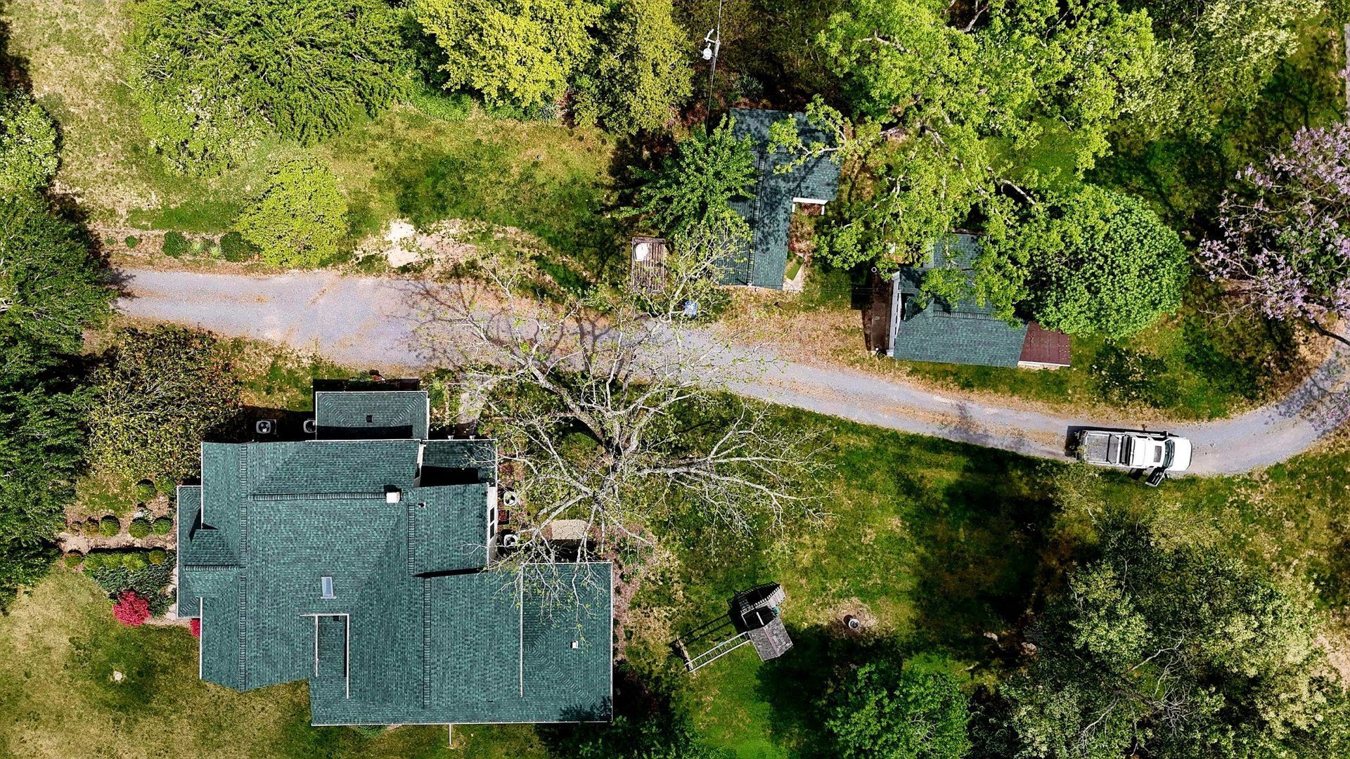 An aerial view of a house surrounded by trees and a road.