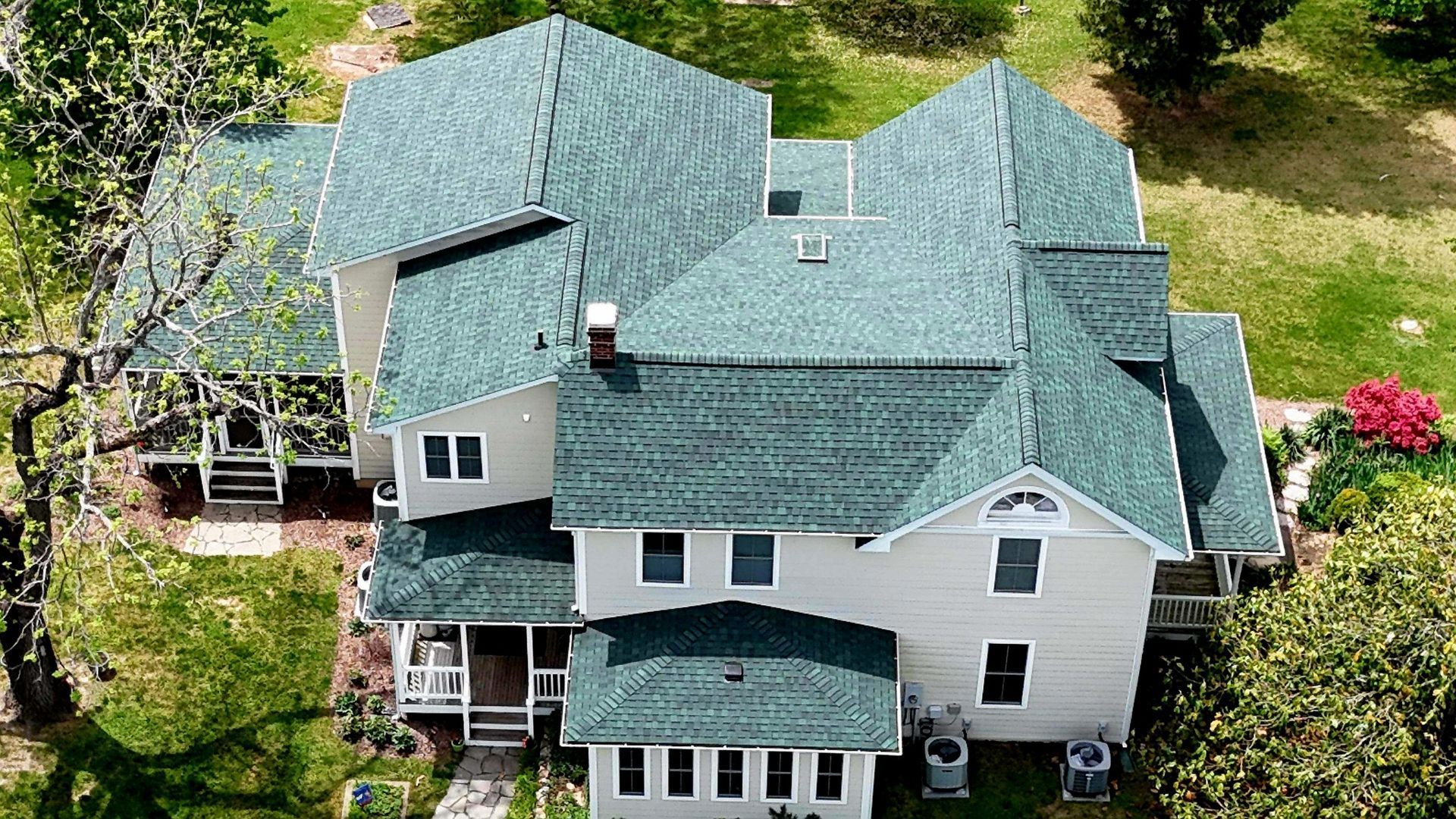 An aerial view of a large white house with a green roof