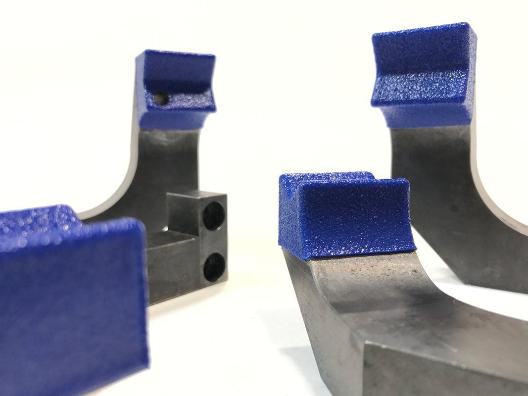 A close up of two metal pieces with blue foam on them on a white surface.