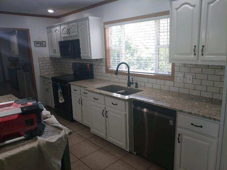 A kitchen with white cabinets , granite counter tops , stainless steel appliances and a sink.