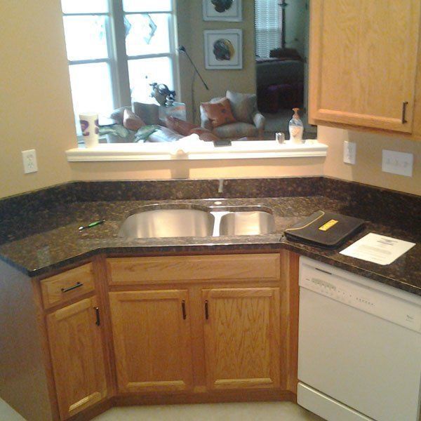 A kitchen with wooden cabinets and a stainless steel sink