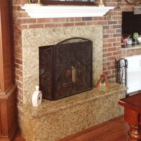 A brick fireplace with a granite mantle and screen