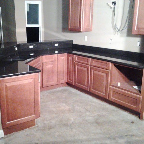 A kitchen with wooden cabinets and black counter tops