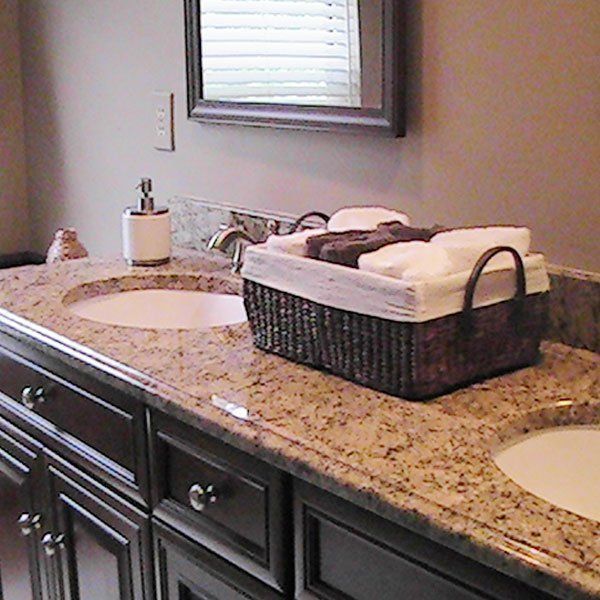 A bathroom counter with two sinks and a basket of towels