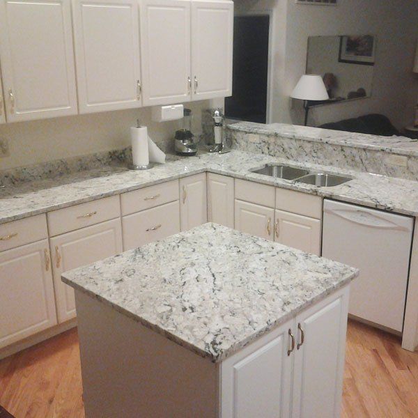 A kitchen with granite counter tops and white cabinets