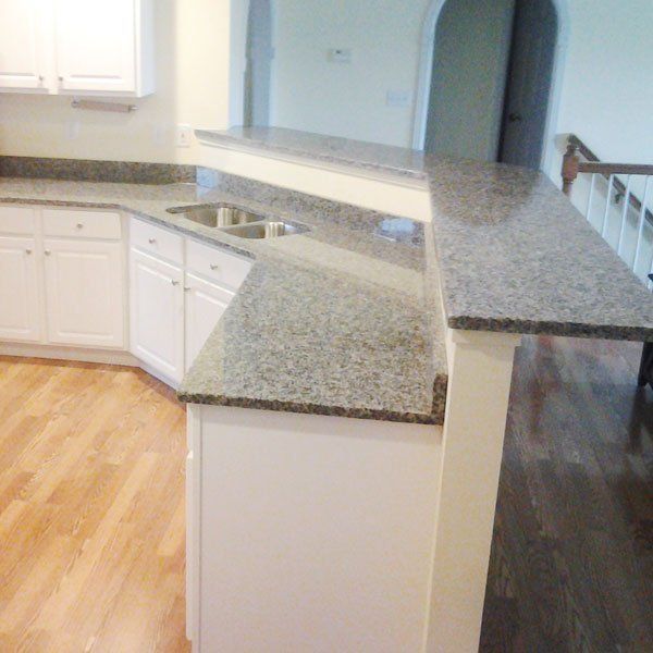 A kitchen with granite counter tops and white cabinets