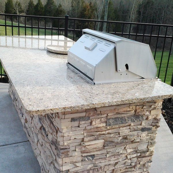 A stainless steel grill sits on top of a granite counter top