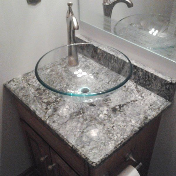 A bathroom sink with a round glass bowl and a faucet