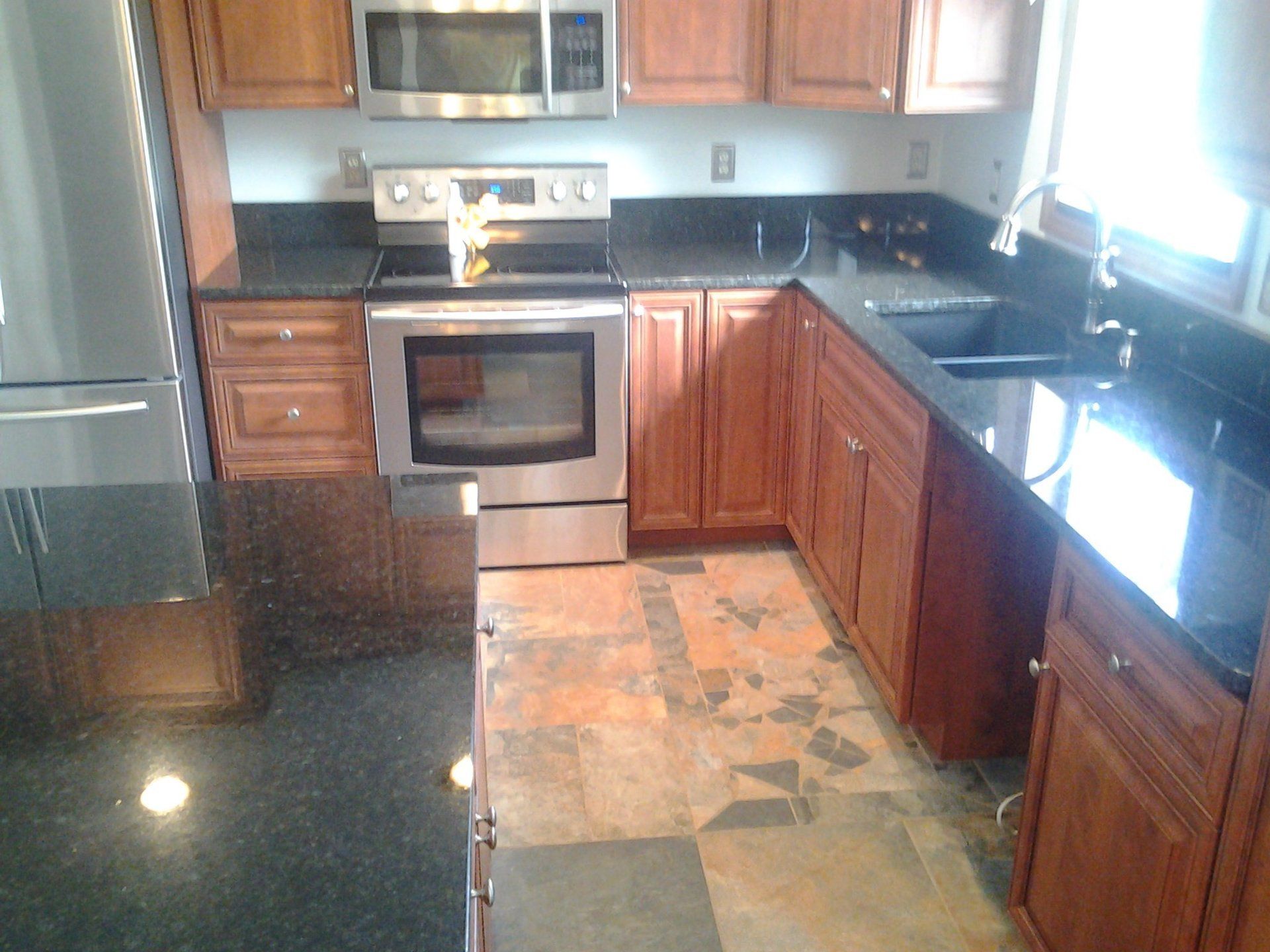 A kitchen with stainless steel appliances and black granite counter tops