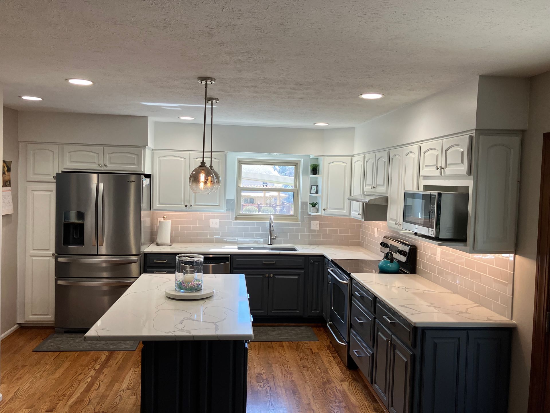 A kitchen with gray cabinets , stainless steel appliances , and a large island.