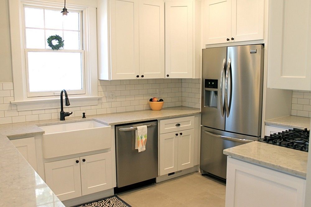 A kitchen with white cabinets , stainless steel appliances , a sink , and a refrigerator.