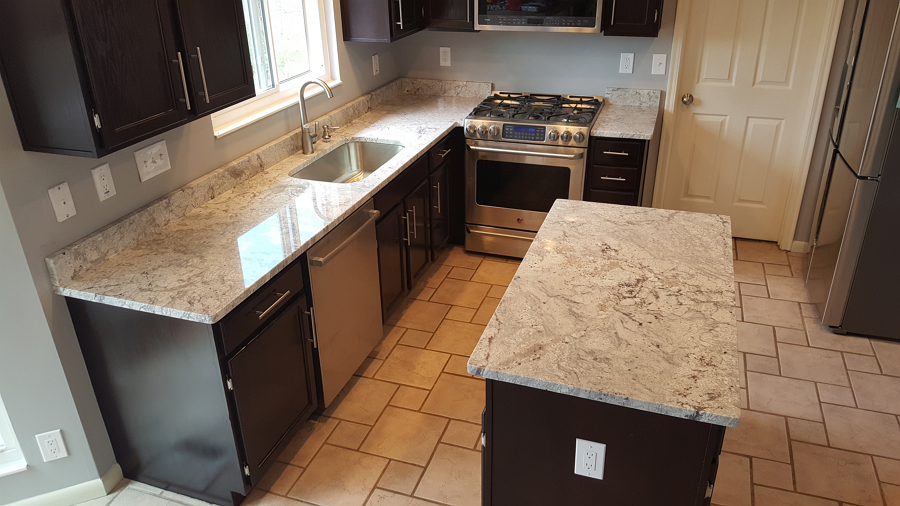 A kitchen with granite counter tops , stainless steel appliances , and black cabinets.