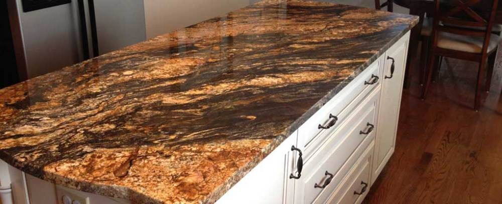 A kitchen island with a granite counter top and white cabinets.