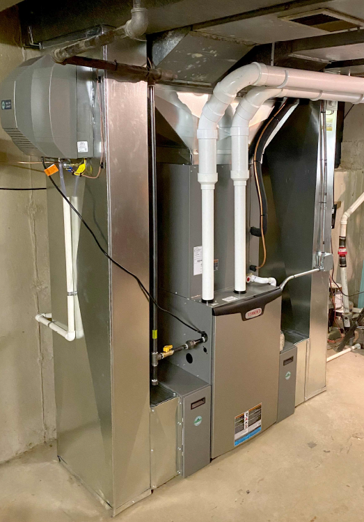Furnace and air conditioning unit in a basement, with ducts and white pipes.