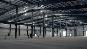A large empty warehouse with a lot of columns and a lot of lights.