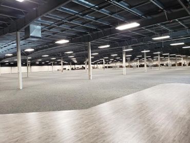 A large empty warehouse with a lot of lights on the ceiling.