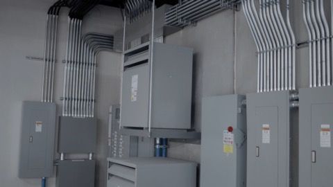 A room with a lot of electrical boxes and wires on the wall.