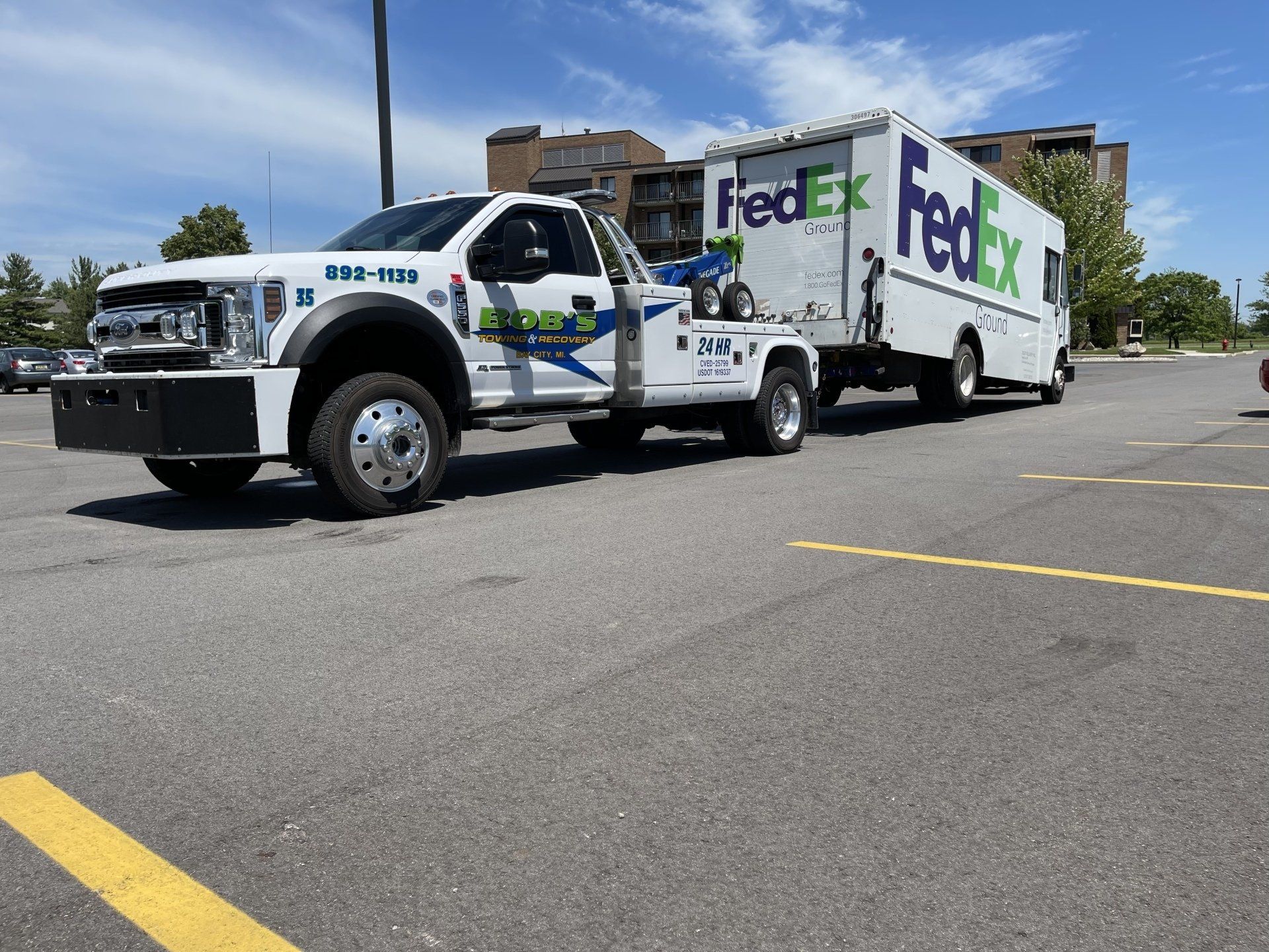 White tow truck with FedEx truck