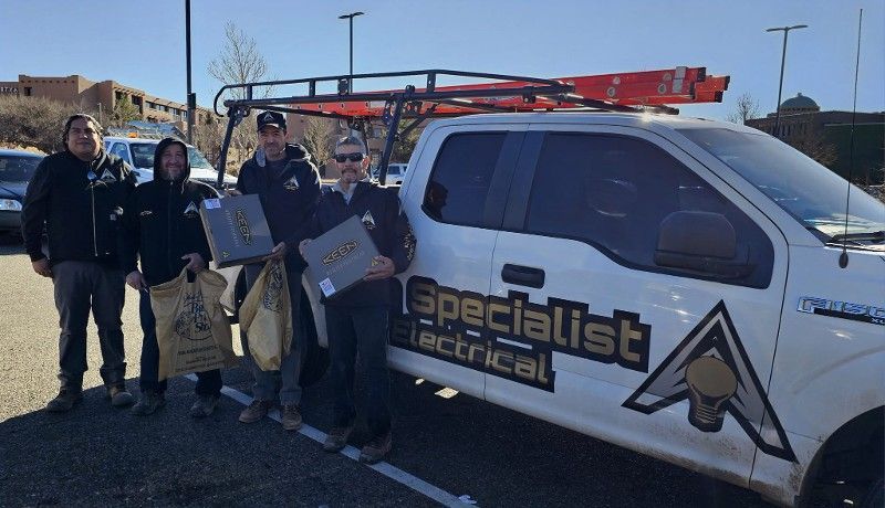 A group of men are standing in front of a truck that says specialist electrical.