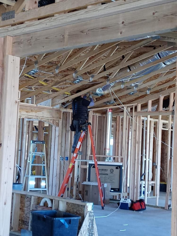 A man is standing on a ladder in a house under construction